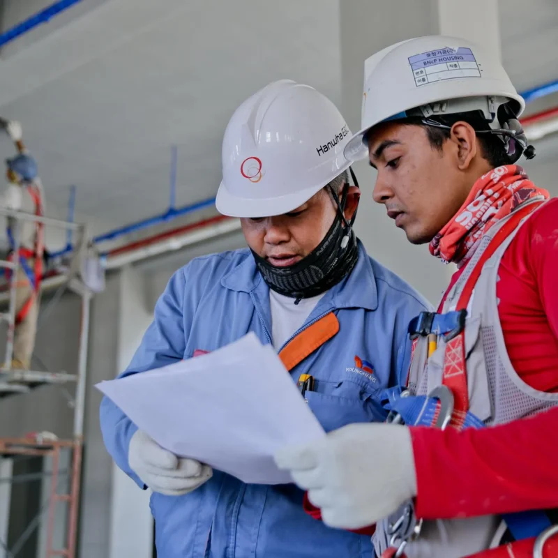Two construction workers review paperwork on-site.
