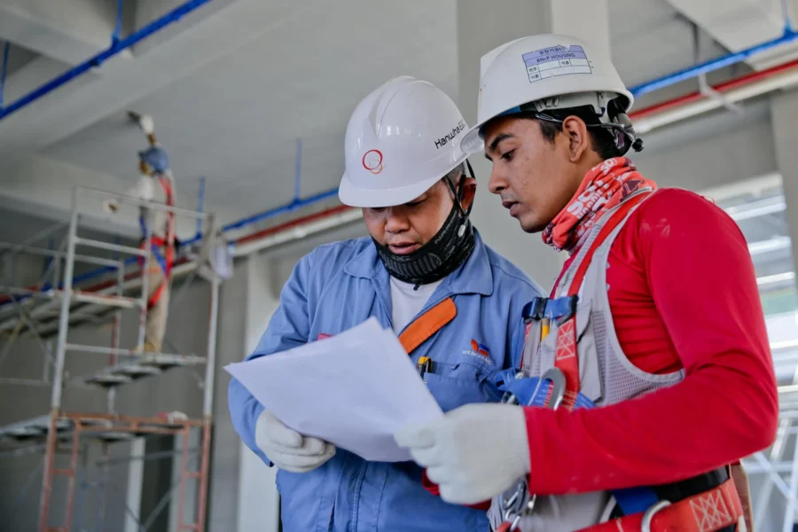 Two construction workers review paperwork on-site.