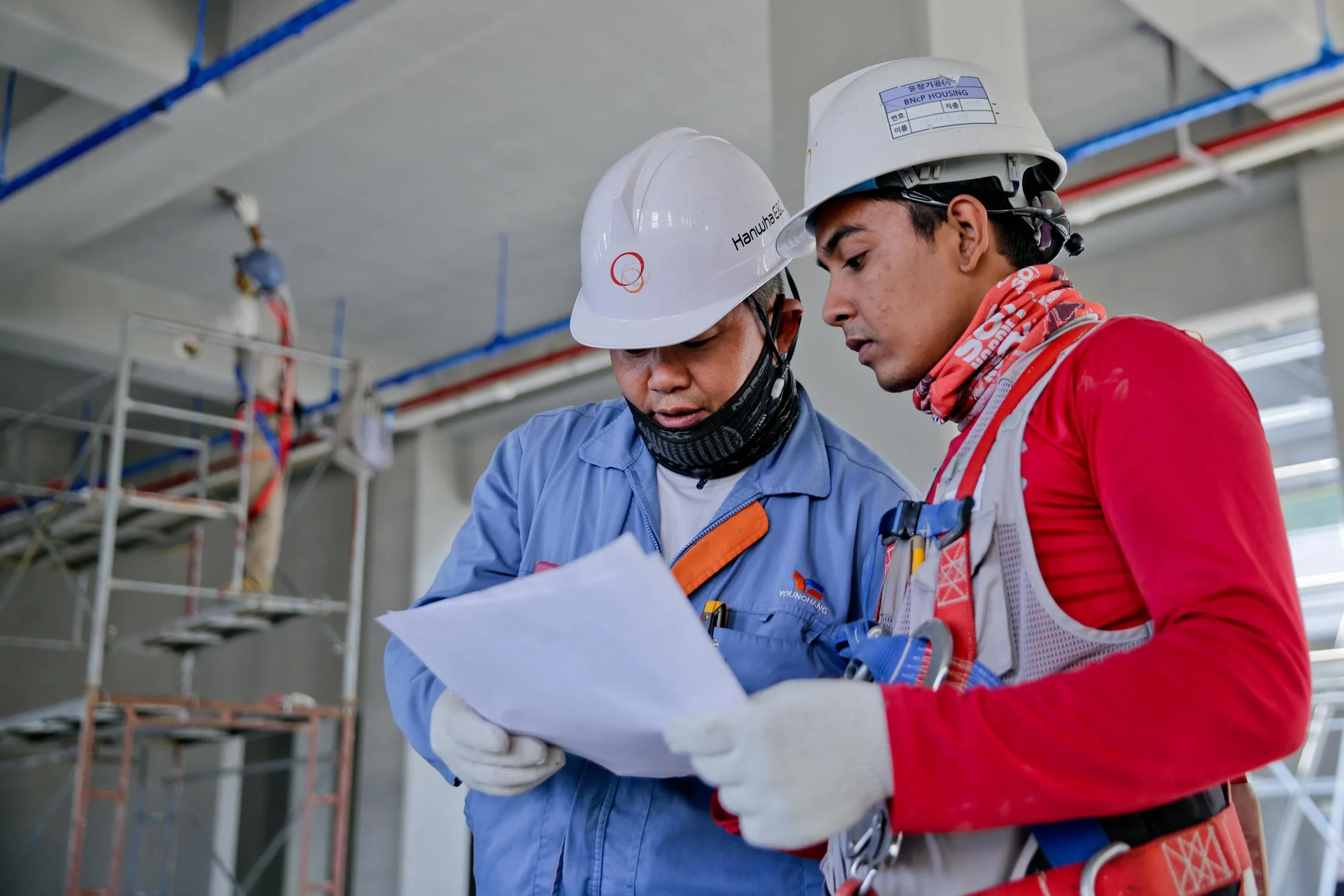 Two construction workers review paperwork on-site.