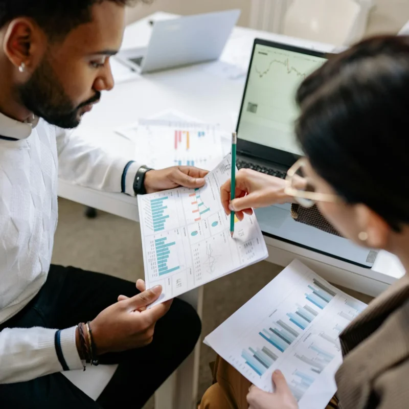 Two project analysts review printed construction reports, highlighting the need for content capture to extract data into actionable digital insights.