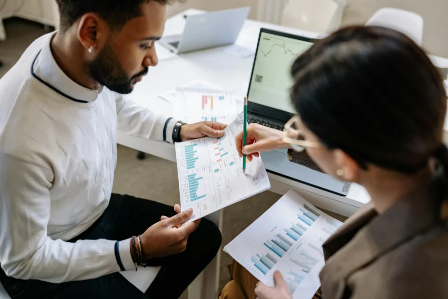 Two project analysts review printed construction reports, highlighting the need for content capture to extract data into actionable digital insights.