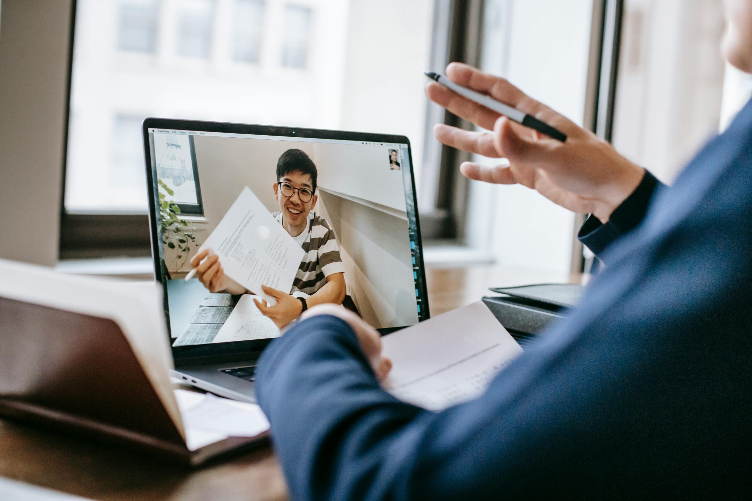 A video call between two professionals demonstrates the collaborative nature of hybrid work and remote communication.
