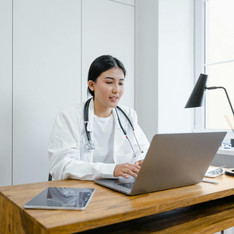 A healthcare professional uses a laptop at her desk, highlighting the role of IT solutions in modern medical practice management.