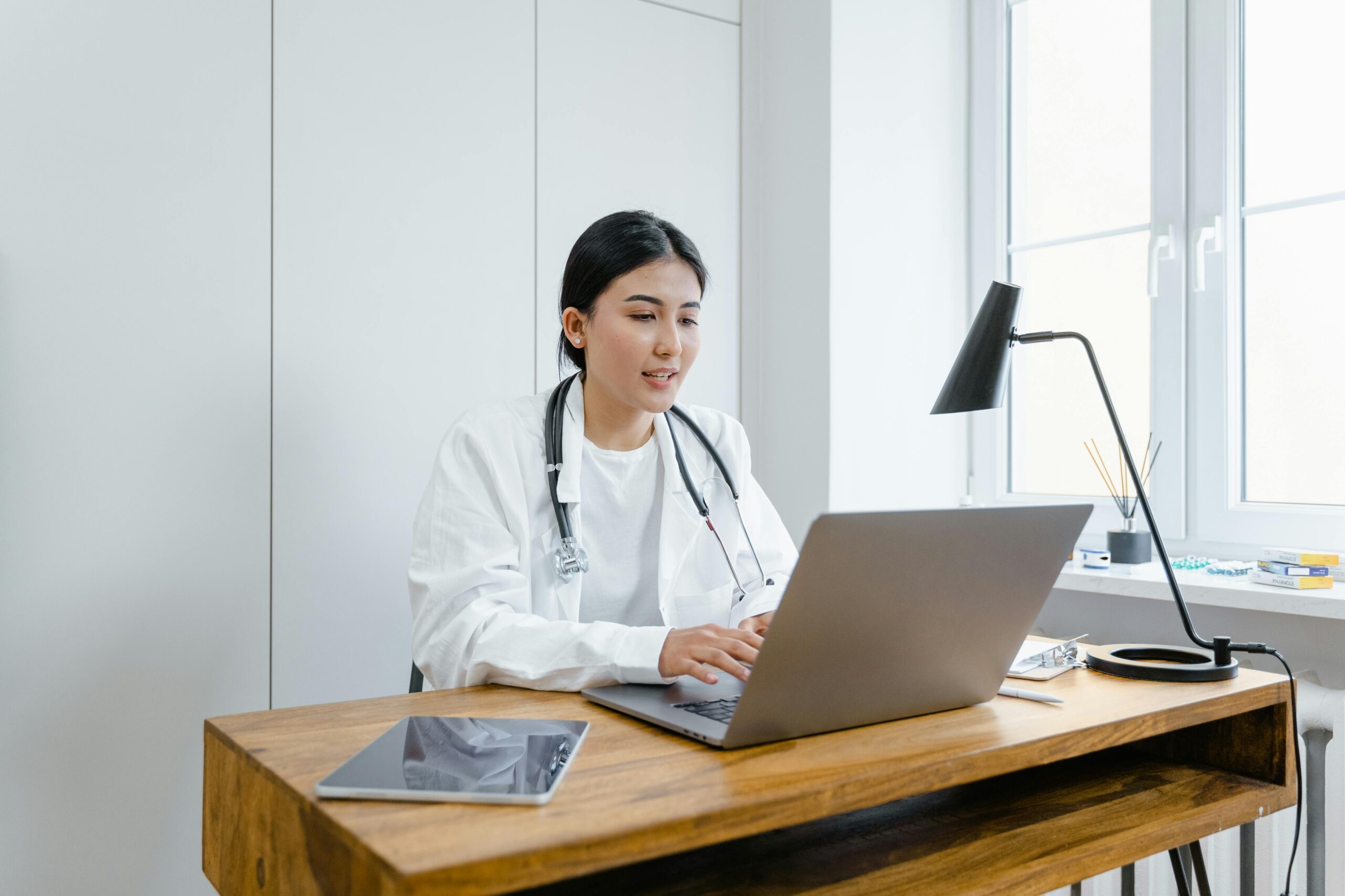 A healthcare professional uses a laptop at her desk, highlighting the role of IT solutions in modern medical practice management.