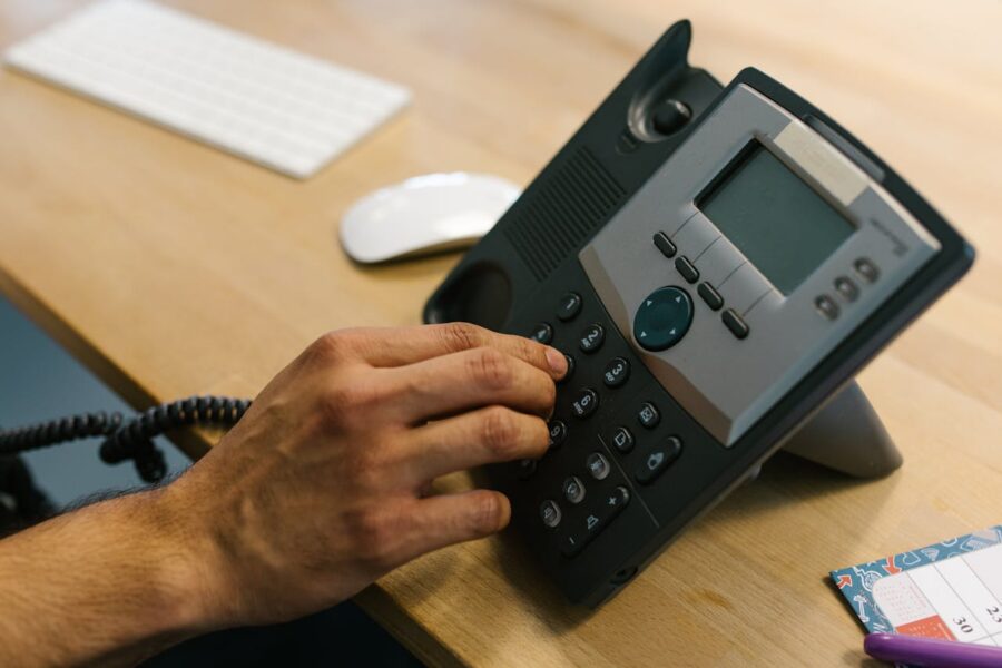 Person dialing a VoIP office phone, demonstrating modern internet-based business communication.