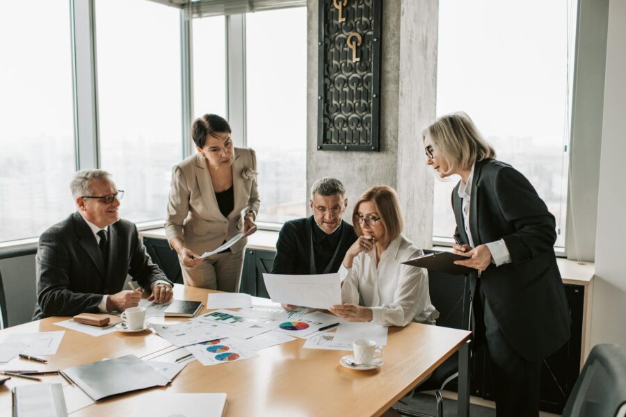 A group of business professionals, reviewing documents and data charts as part of a comprehensive cyber risk assessment meeting.