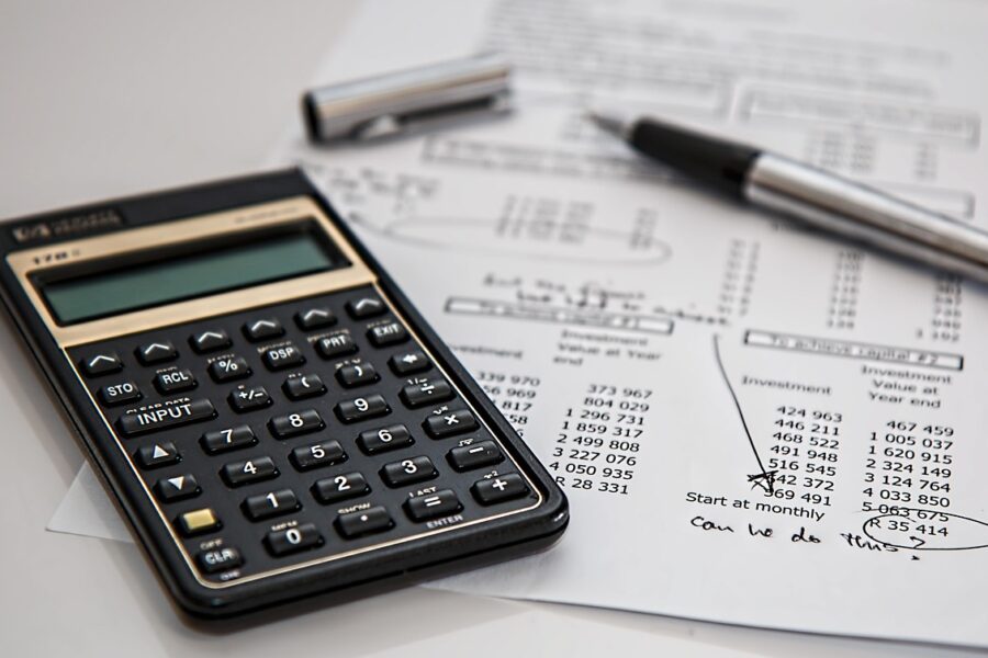 A calculator, pen, and financial report with handwritten notes suggest a business evaluating costs and coverage options for cyber insurance.