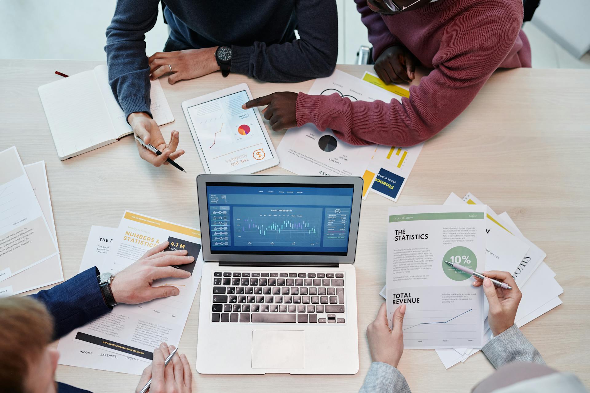 A team works together at a table using laptops and tablets, showing how digital collaboration tools help simplify communication and teamwork.