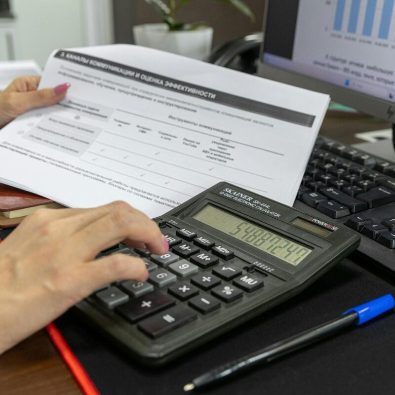 Employee manually calculating invoices on paper instead of using custom automation tools.
