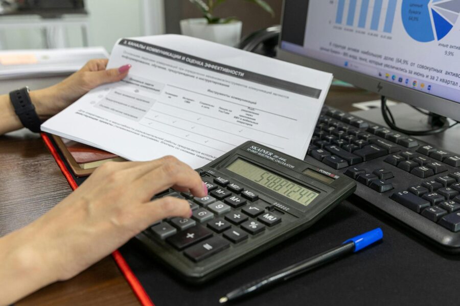 Employee manually calculating invoices on paper instead of using custom automation tools.