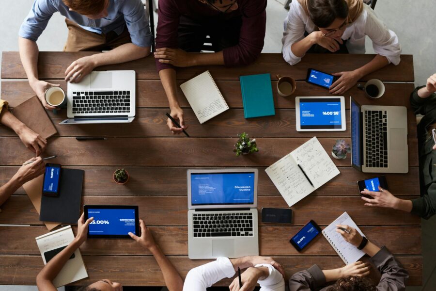 Team collaborating on cloud software development using laptops, tablets, and smartphones around a table.