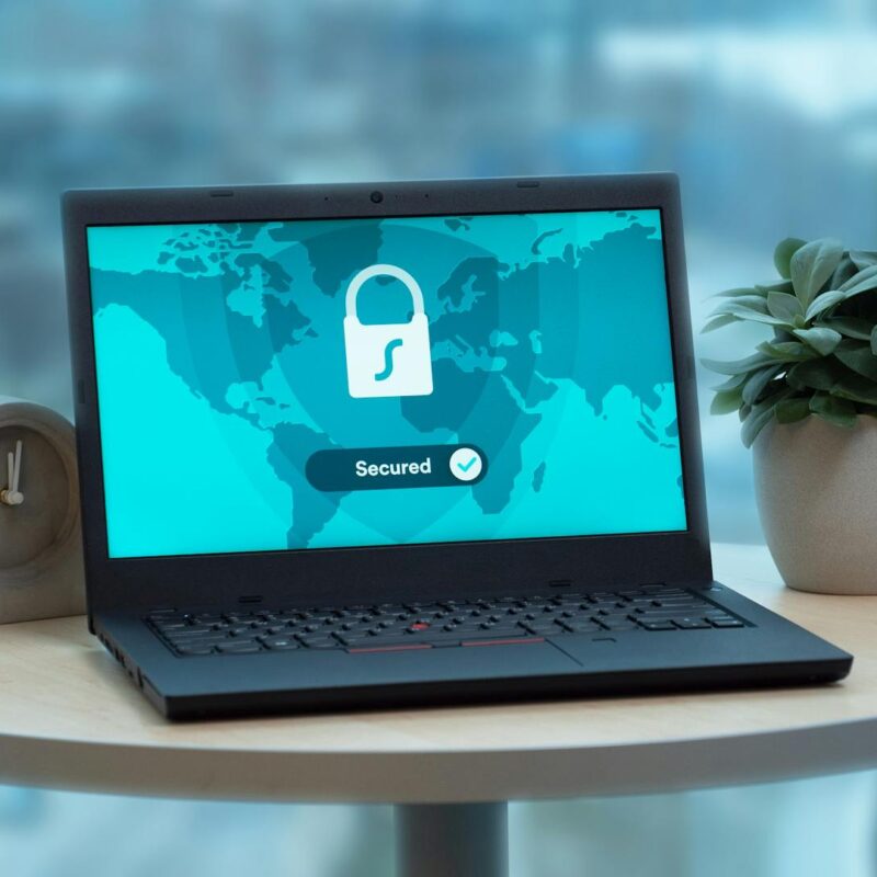 Laptop on round table with documents, symbolizing cyber risk review and insurance analysis