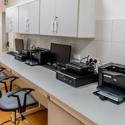 A modern office workspace with multiple printers and computers organized for efficient logistics print management.