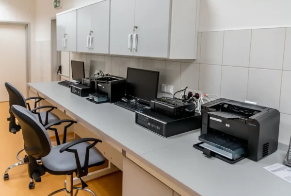 A modern office workspace with multiple printers and computers organized for efficient logistics print management.