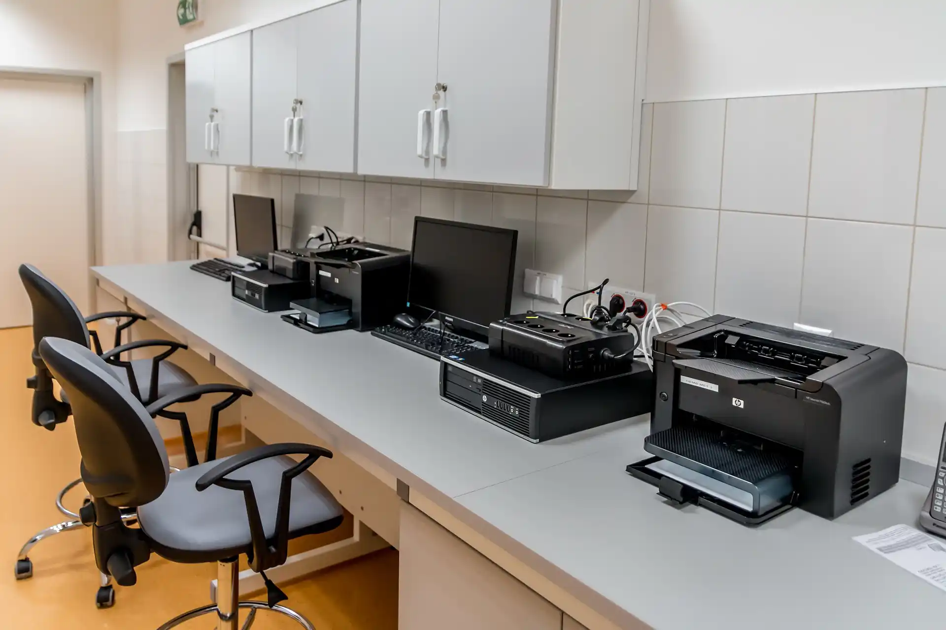 A modern office workspace with multiple printers and computers organized for efficient logistics print management.