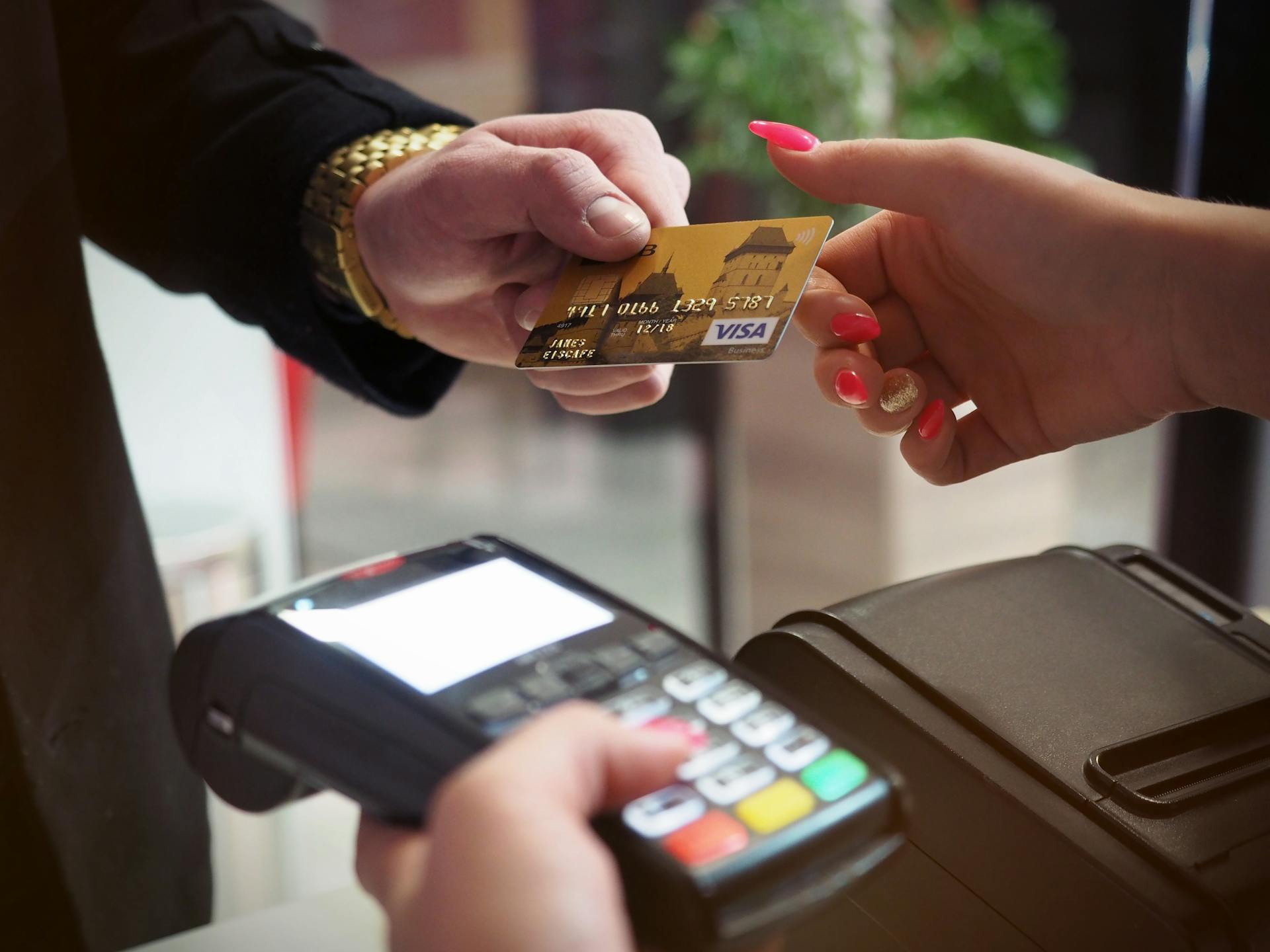Person handing over a credit card at a payment terminal.