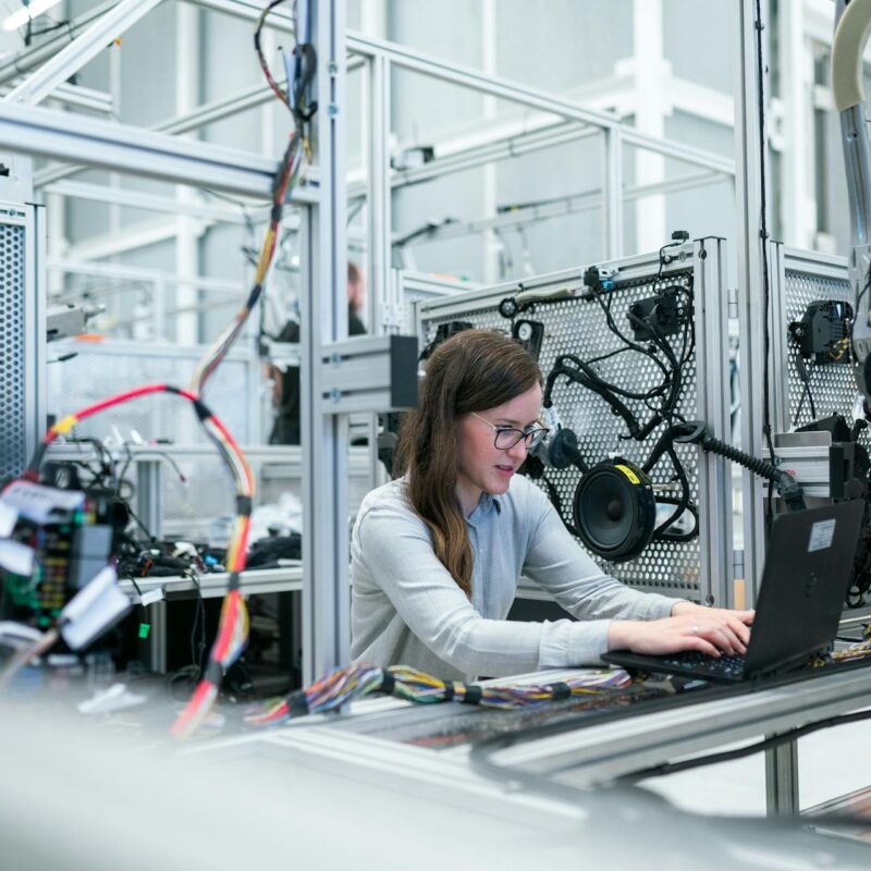 A female engineer working on connected systems in a high-tech lab, illustrating secure data handling and CMMC compliance for manufacturers