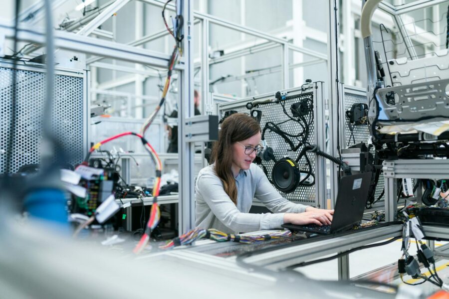 A female engineer working on connected systems in a high-tech lab, illustrating secure data handling and CMMC compliance for manufacturers