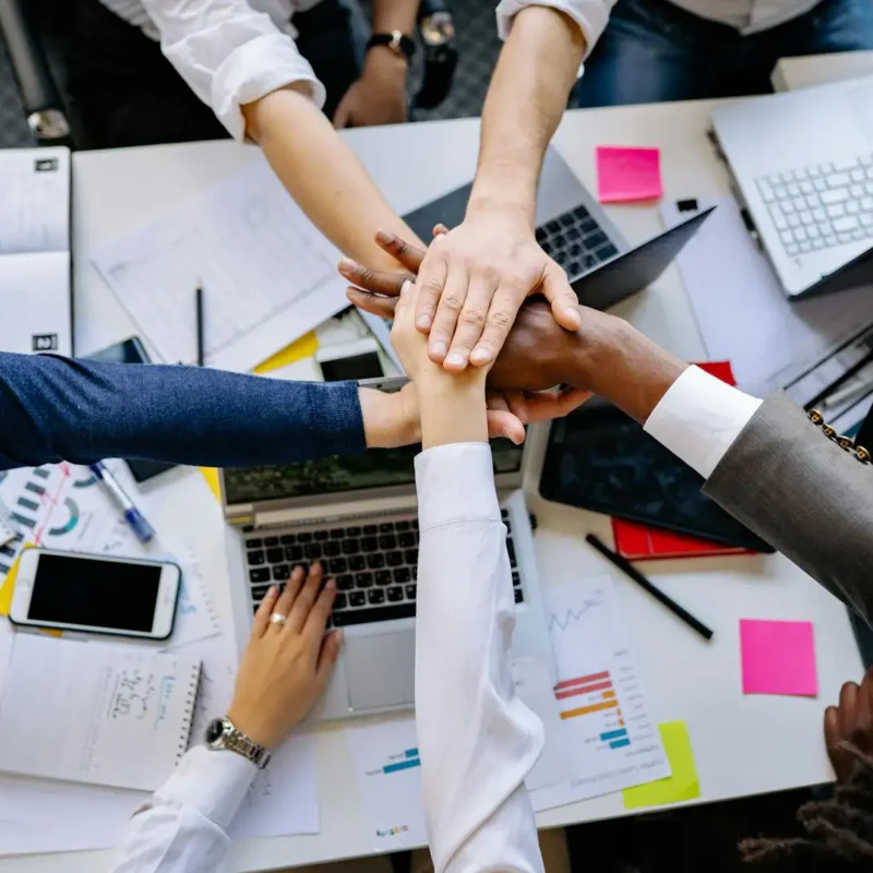 A team collaborates around laptops and documents, using AI tools to improve teamwork and efficiency.