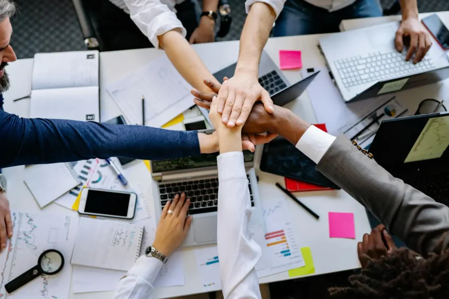 A team collaborates around laptops and documents, using AI tools to improve teamwork and efficiency.