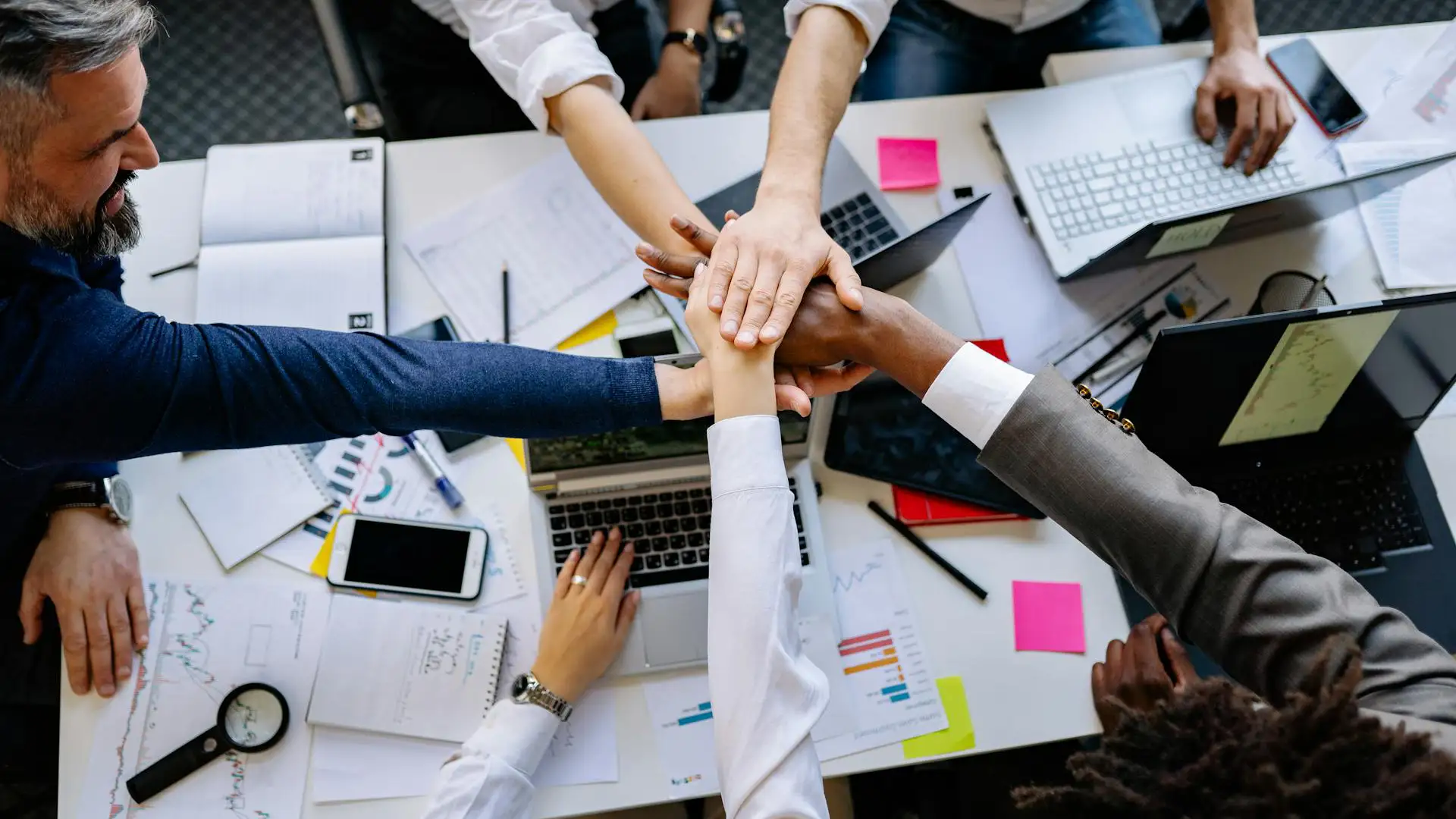 A team collaborates around laptops and documents, using AI tools to improve teamwork and efficiency.