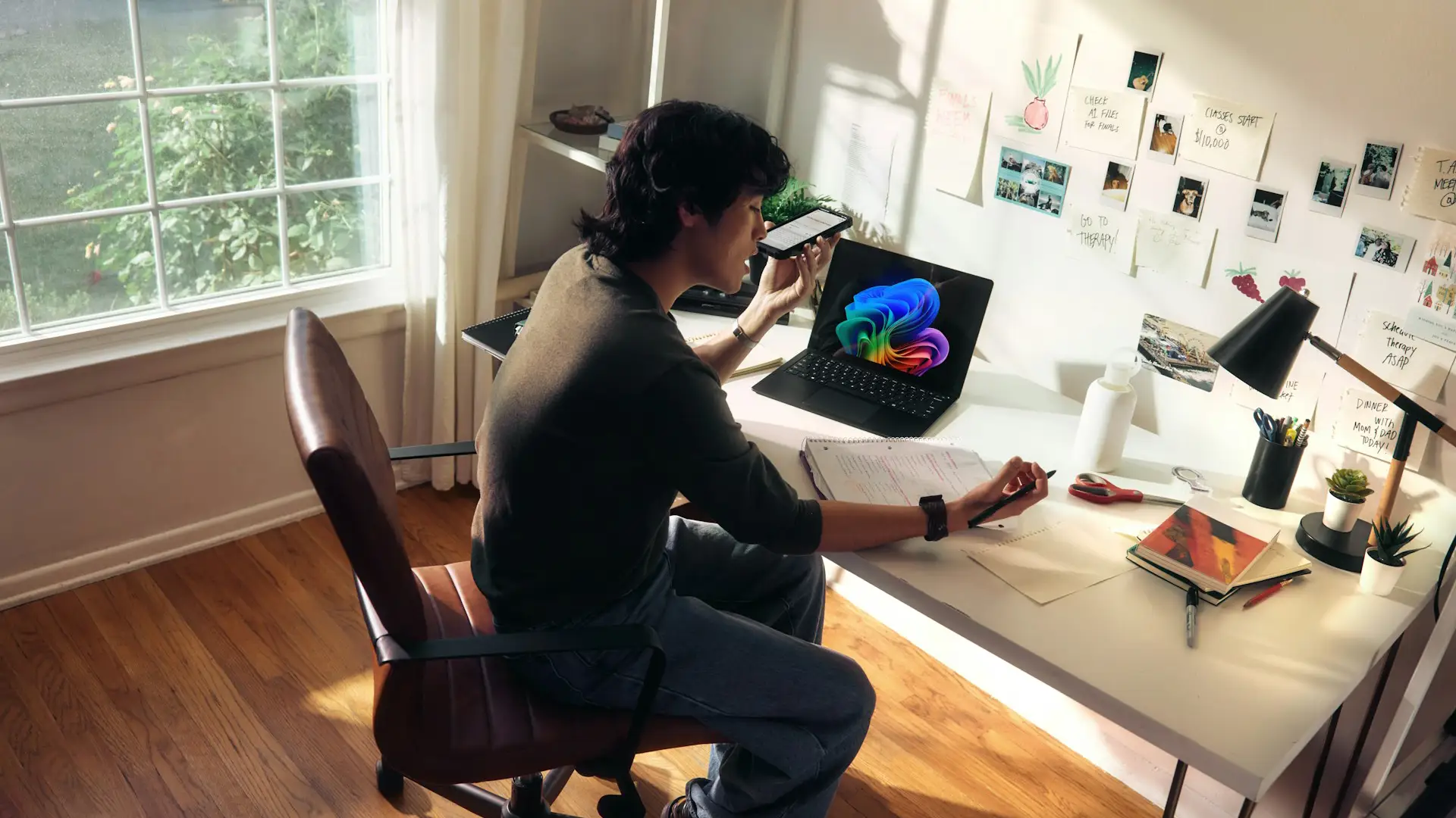 Person working at a desk using AI Copilot on a laptop while referencing notes and a smartphone for AI-assisted decision-making.