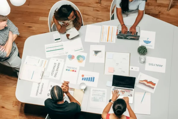 Marketing team collaborates over data-driven campaign assets and charts, leveraging AI marketing insights to plan and optimize strategy.