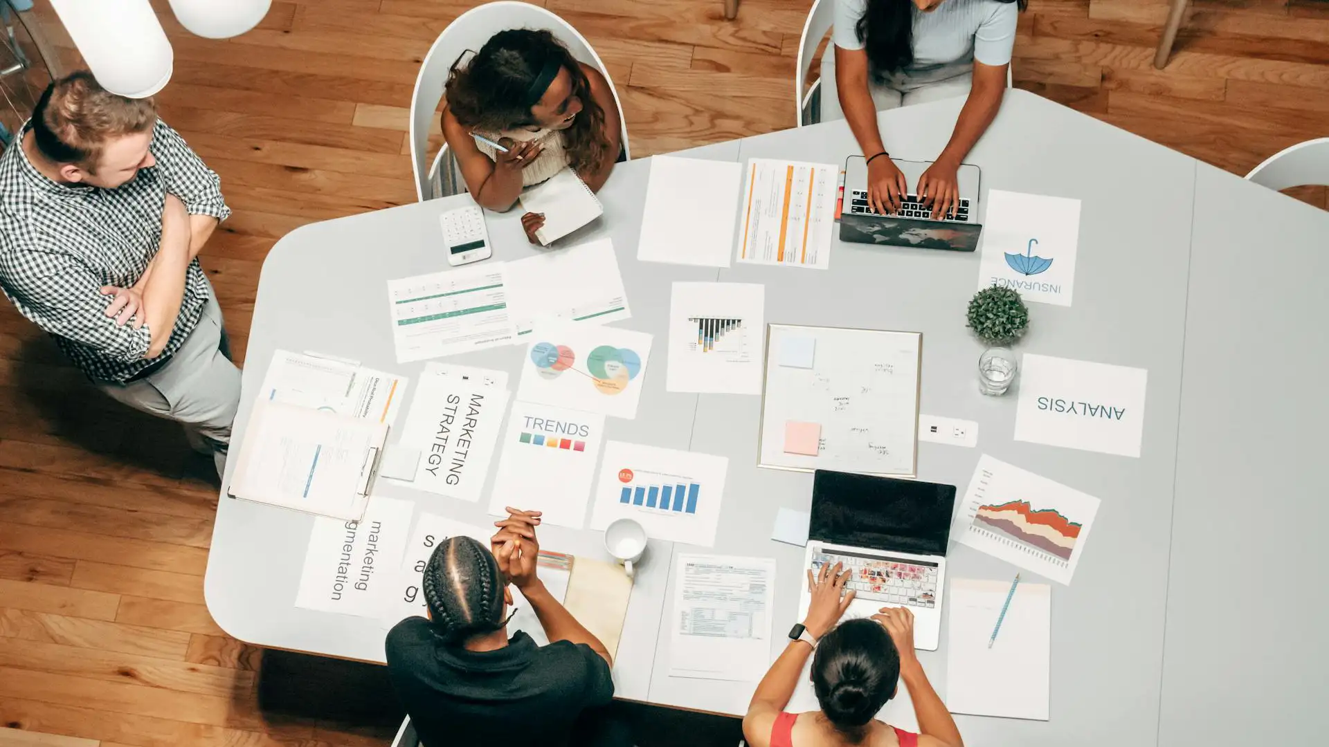 Marketing team collaborates over data-driven campaign assets and charts, leveraging AI marketing insights to plan and optimize strategy.