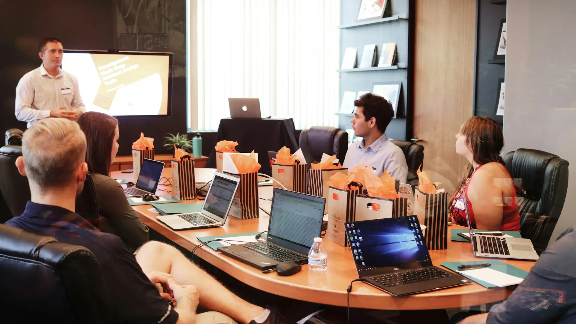 Team collaborating in a modern conference room with laptops, shared display, and hybrid meeting setup enabled by conference room technology.
