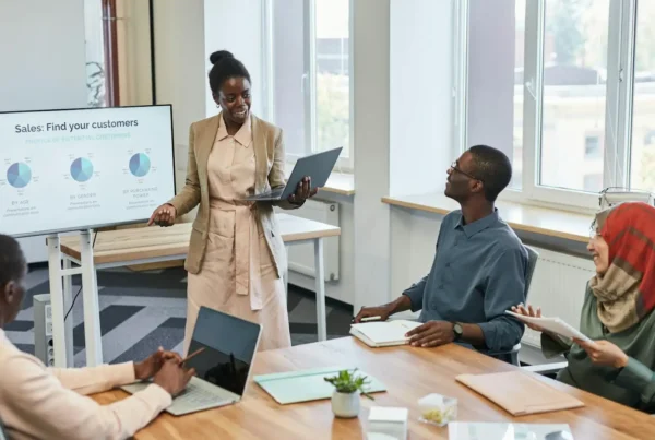 A presenter leads a data-driven pitch meeting, using AI tools to visualize customer demographics on a digital display.