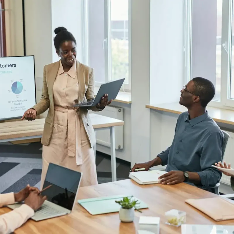 A presenter leads a data-driven pitch meeting, using AI tools to visualize customer demographics on a digital display.