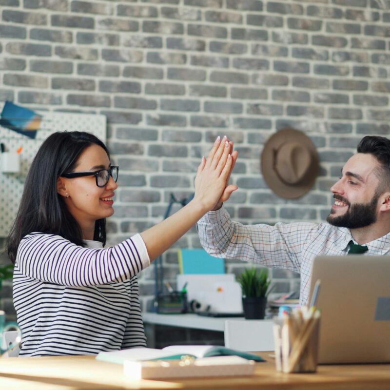 Two professionals high-fiving in an office, symbolizing trust, collaboration, and responsible AI use with Copilot.