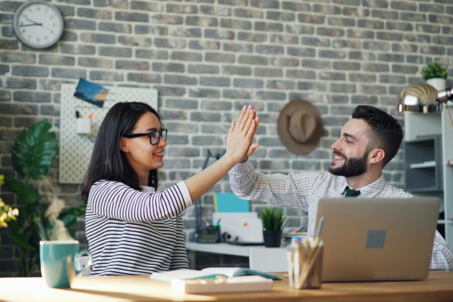 Two professionals high-fiving in an office, symbolizing trust, collaboration, and responsible AI use with Copilot.