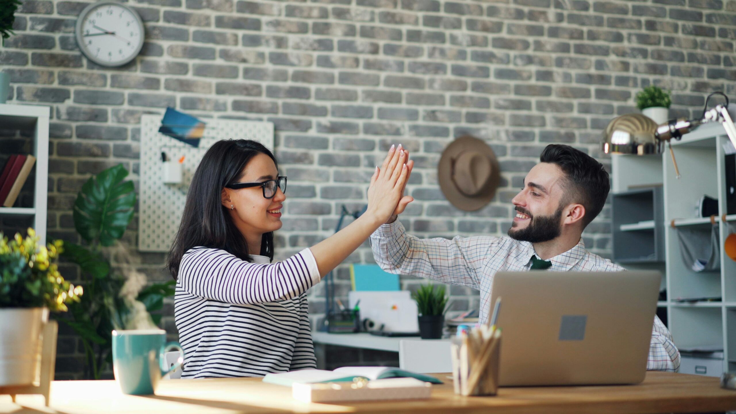 Two professionals high-fiving in an office, symbolizing trust, collaboration, and responsible AI use with Copilot.