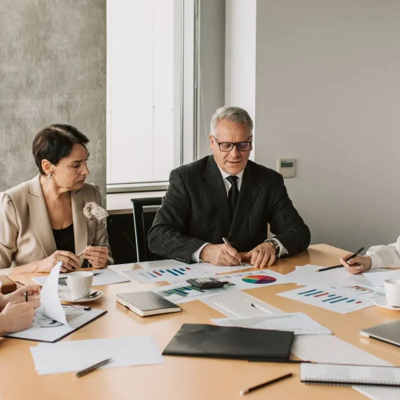 A business execution strategy meeting where executives collaborate over performance charts and reports.