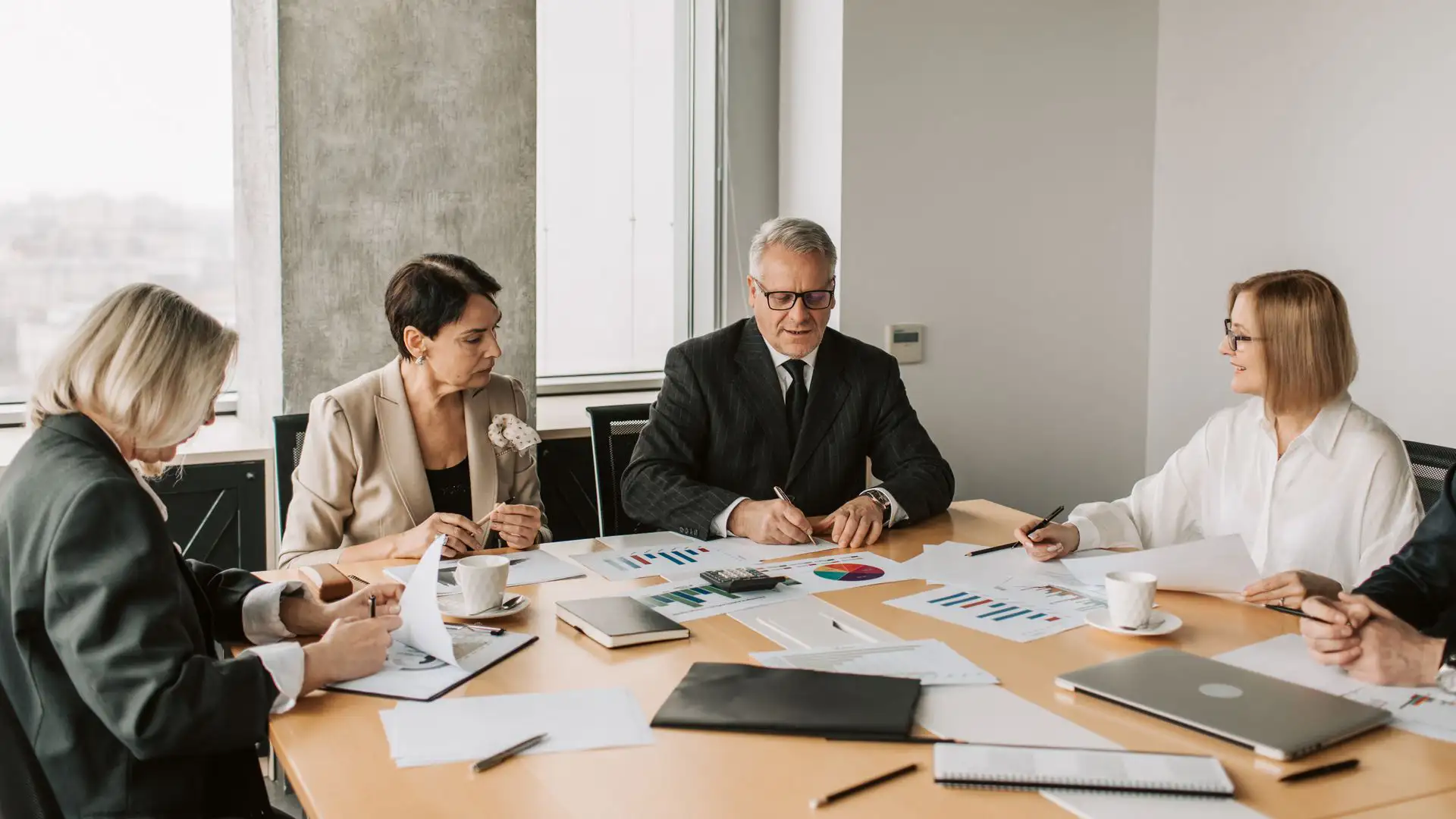 A business execution strategy meeting where executives collaborate over performance charts and reports.