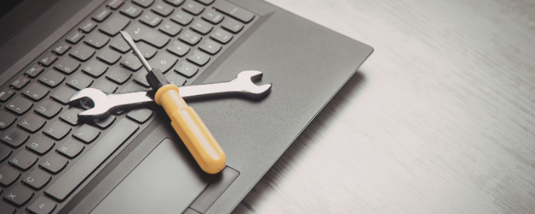 A laptop with tools sitting on the keyboard representing Manage IT services.