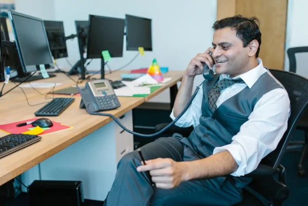 An office employee using an efficient business phone system to speak with a client.