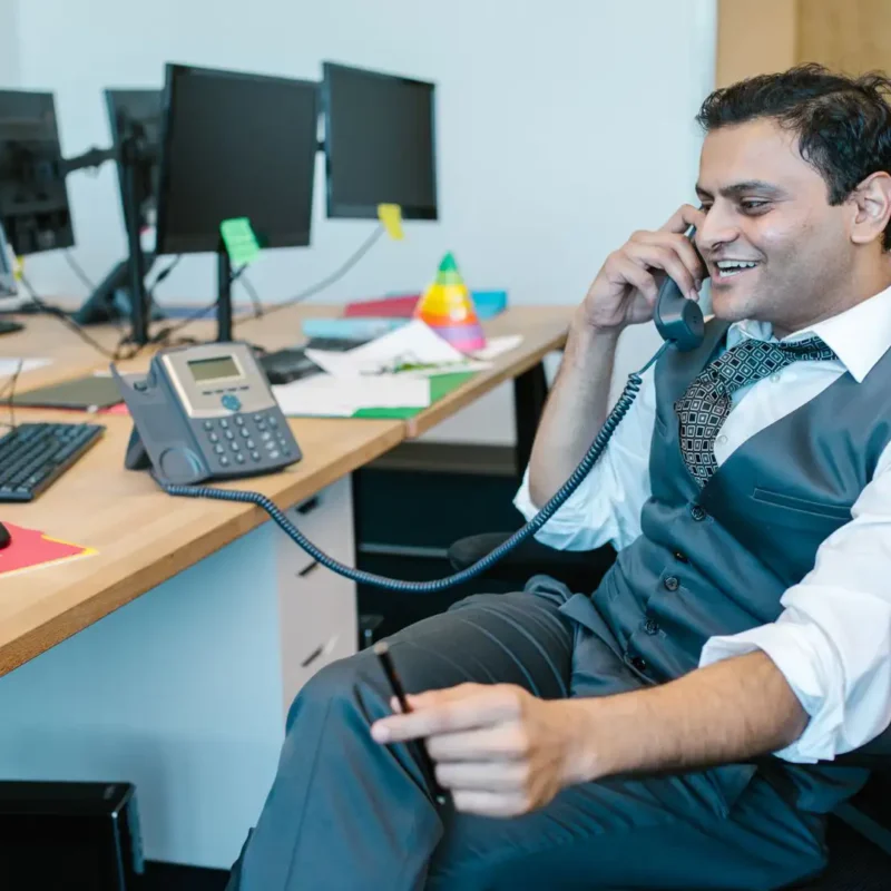 An office employee using an efficient business phone system to speak with a client.