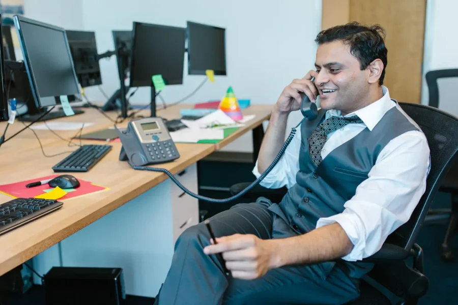 An office employee using an efficient business phone system to speak with a client.