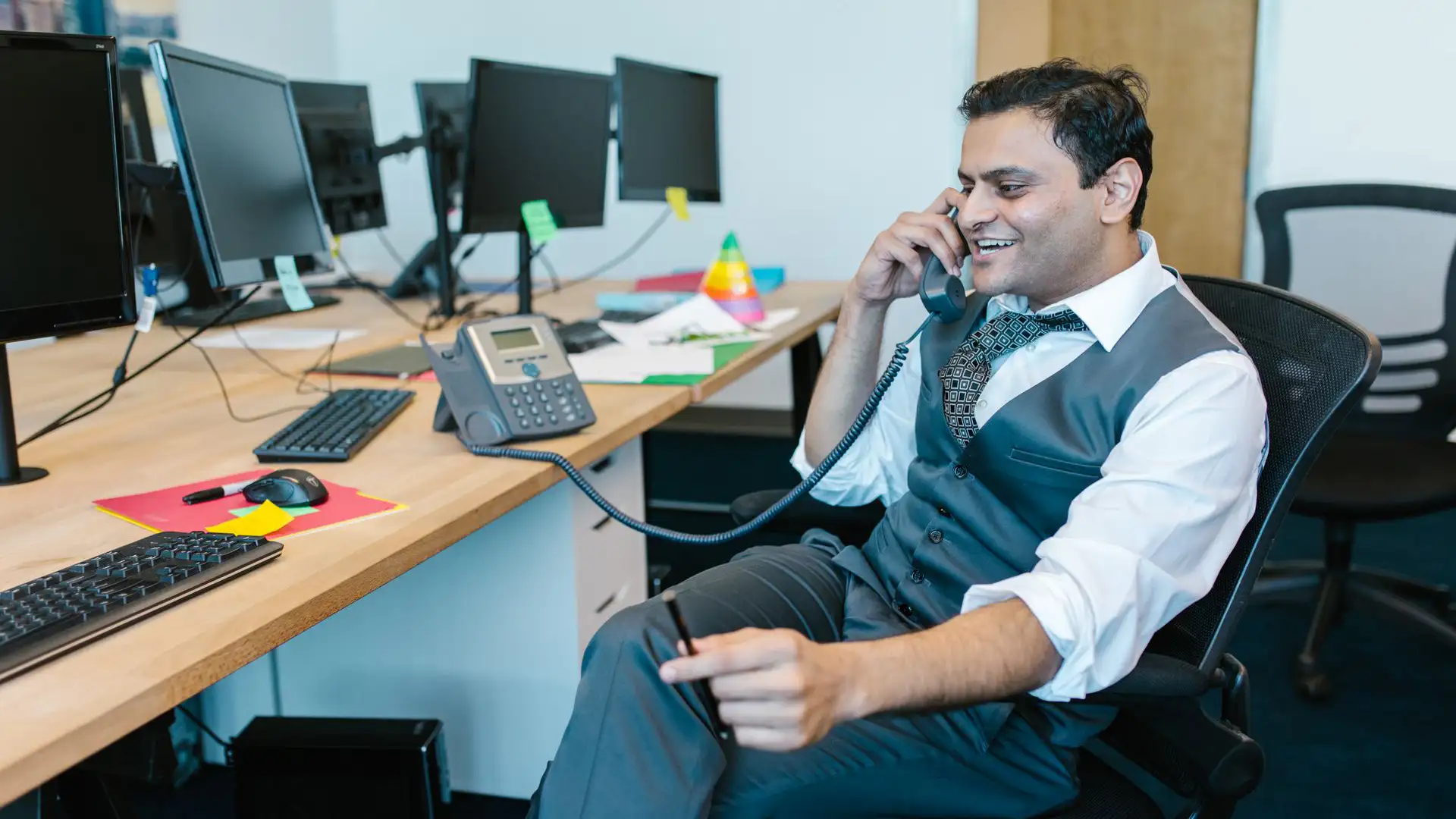 An office employee using an efficient business phone system to speak with a client.