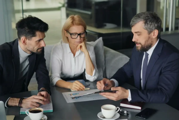 An IT provider consultant reviews documents and data reports during a business meeting with clients.