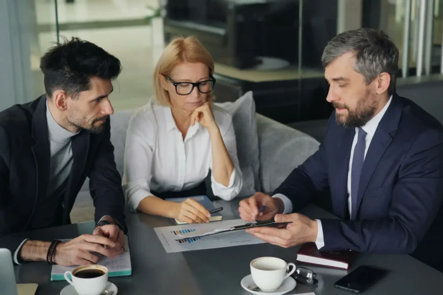 An IT provider consultant reviews documents and data reports during a business meeting with clients.