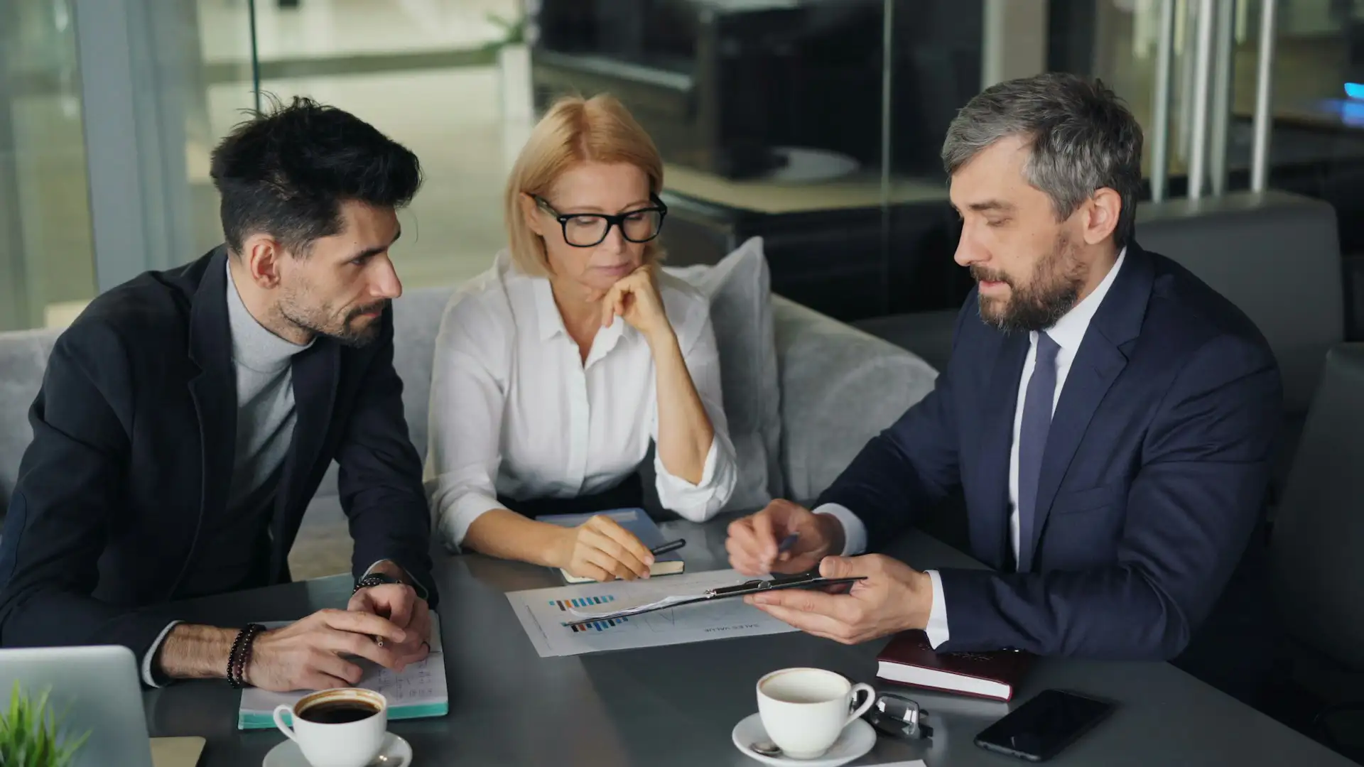 An IT provider consultant reviews documents and data reports during a business meeting with clients.
