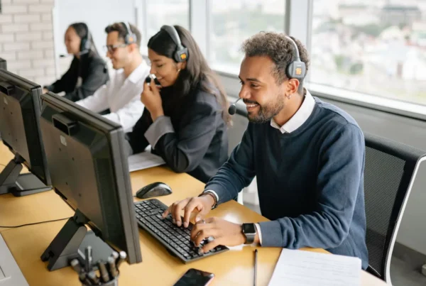A team of agents wearing headsets and working on computers at a row of desks in a contact center.