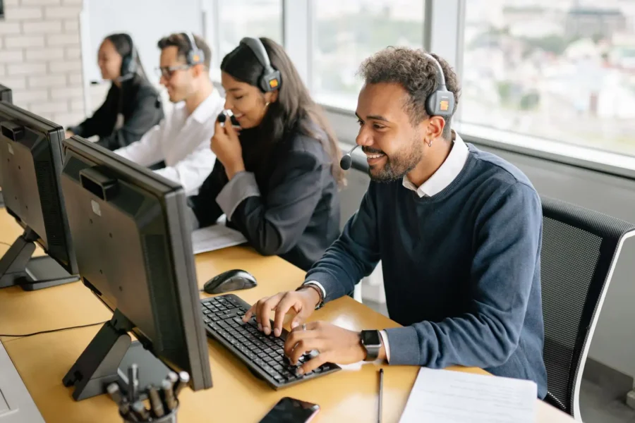 A team of agents wearing headsets and working on computers at a row of desks in a contact center.